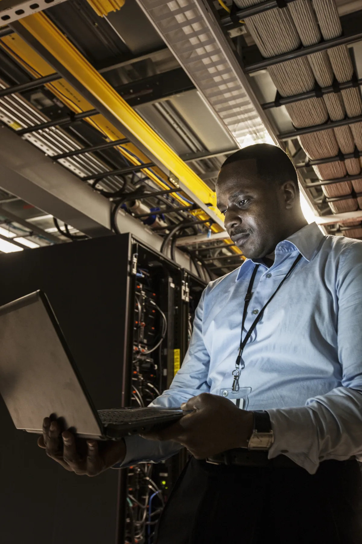 An engineer working at a laptop beside a live server rack