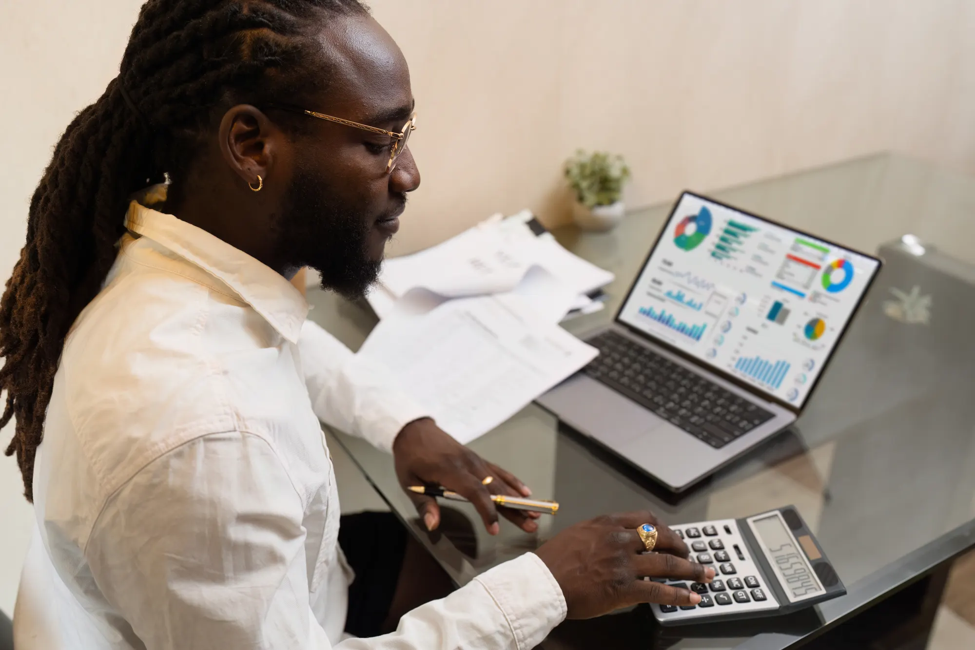 A business owner reviewing financial charts on a laptop beside a calculator